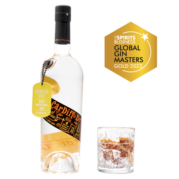 A 70cl bottle of Eccentric Spirit Co's Cardiff Dry Welsh Gin alongside an old fashioned glass half-filled with the Welsh gin and grapefruit garnish. A Gold Medal is displayed in the corner which was awarded to this Welsh gin at the Global Gin Masters 2022.