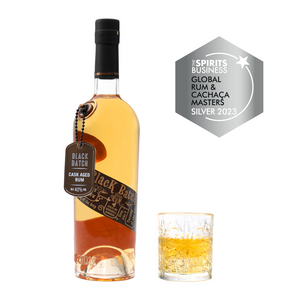 A 70cl bottle of Eccentric Spirit Co's Black Batch Cask Aged Welsh Rum alongside an old fashioned glass half-filled with the Welsh spiced rum. A Silver Medal is displayed in the corner which was awarded to this Welsh spiced rum at the Global Rum & Cachaça Masters 2023.