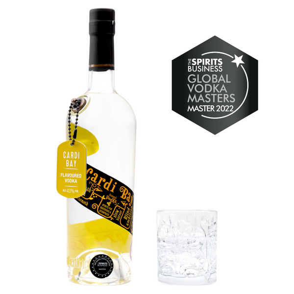 A 70cl bottle of Eccentric Spirit Co's Cardi Bay Welsh Flavoured Vodka alongside an old fashioned glass half-filled with the Welsh flavoured vodka. A Master Medal is displayed in the corner which was awarded to this Welsh vodka at the Global Vodka Masters 2022.