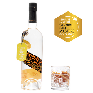 A 70cl bottle of Eccentric Spirit Co's Cardiff Dry Welsh Gin alongside an old fashioned glass half-filled with the Welsh gin and grapefruit garnish. A Gold Medal is displayed in the corner which was awarded to this Welsh gin at the Global Gin Masters 2022.