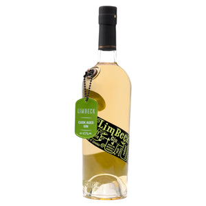 A 70cl bottle of Eccentric Spirit Co's Limbeck Cask Aged Welsh Gin with a white background. This Welsh gin has a green dog tag dangling from the bottle and a distinctive black and green label, which complements the subtle peach colour of the gin and tells the story of what inspired the creation of this Welsh gin.