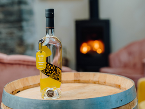 Our Master award-winning Cardi Bay Flavoured Welsh Vodka stood on a barrel with a fire burning in the background.
